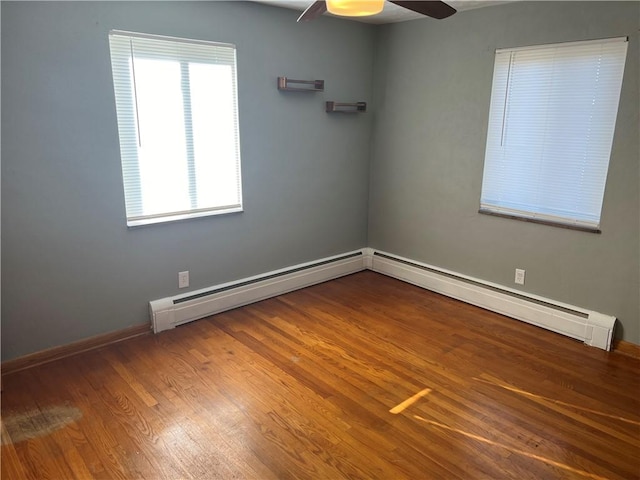 empty room featuring hardwood / wood-style flooring, ceiling fan, and a baseboard heating unit