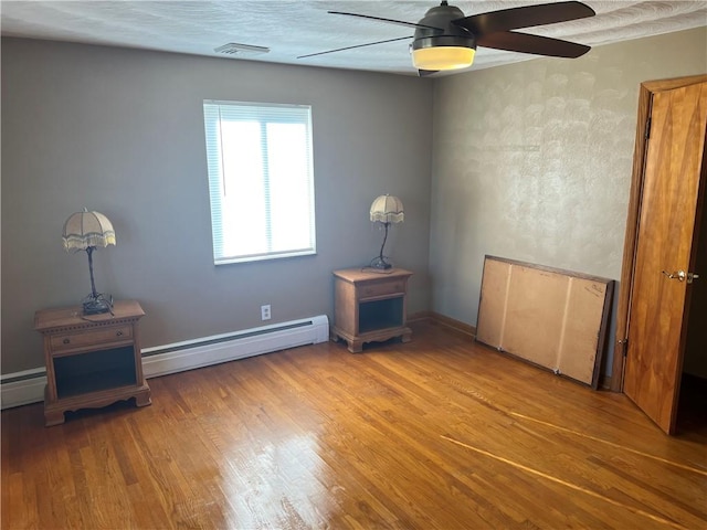 spare room featuring wood-type flooring, a baseboard radiator, and ceiling fan