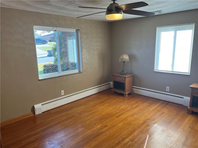 spare room featuring hardwood / wood-style floors, plenty of natural light, and a baseboard heating unit