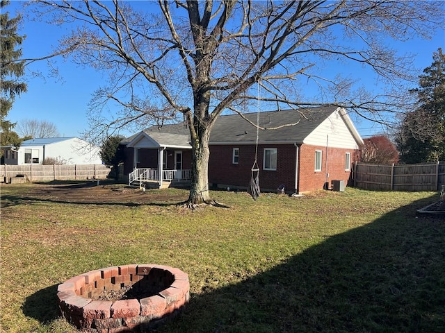 rear view of property featuring a yard, covered porch, and a fire pit