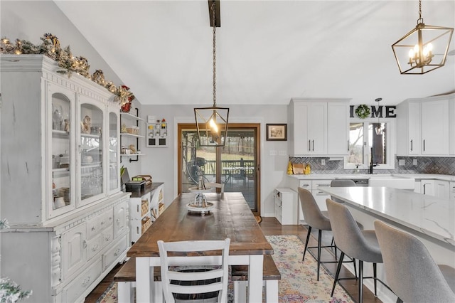 kitchen with light stone countertops, white cabinetry, pendant lighting, lofted ceiling, and decorative backsplash