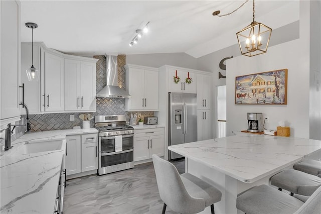 kitchen featuring pendant lighting, backsplash, wall chimney range hood, appliances with stainless steel finishes, and a breakfast bar area