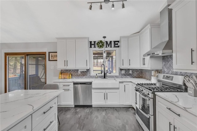 kitchen featuring white cabinetry, sink, stainless steel appliances, wall chimney range hood, and decorative backsplash