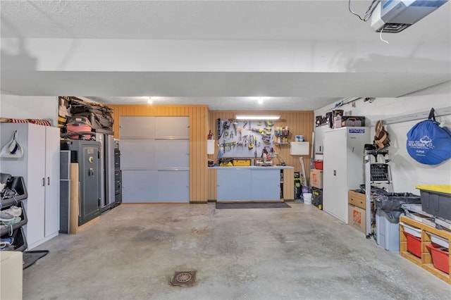 garage with a workshop area, a garage door opener, and wooden walls