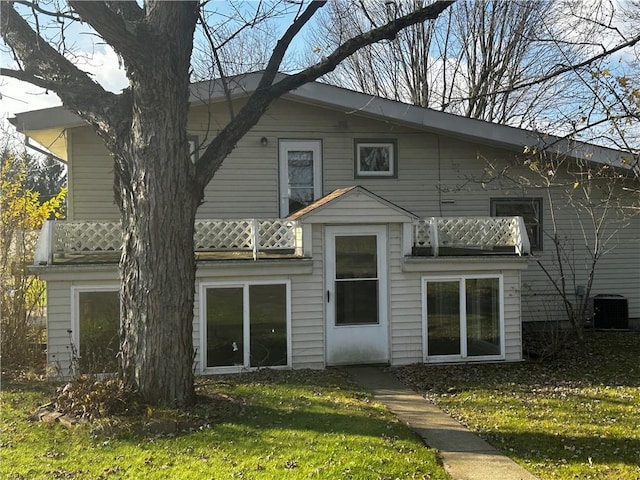 back of property featuring a lawn, cooling unit, and a balcony