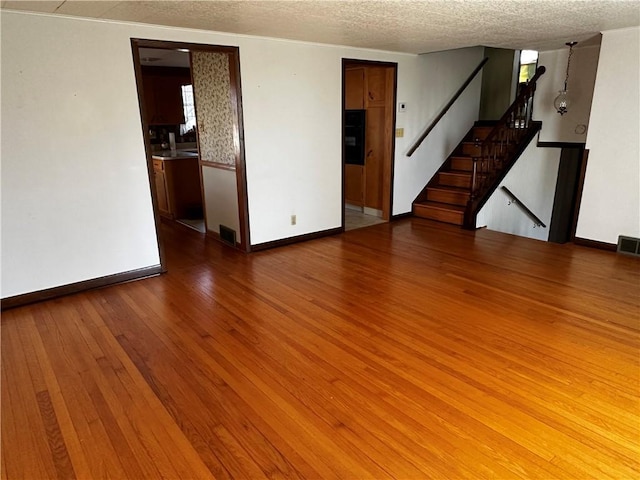 empty room featuring a textured ceiling and light wood-type flooring