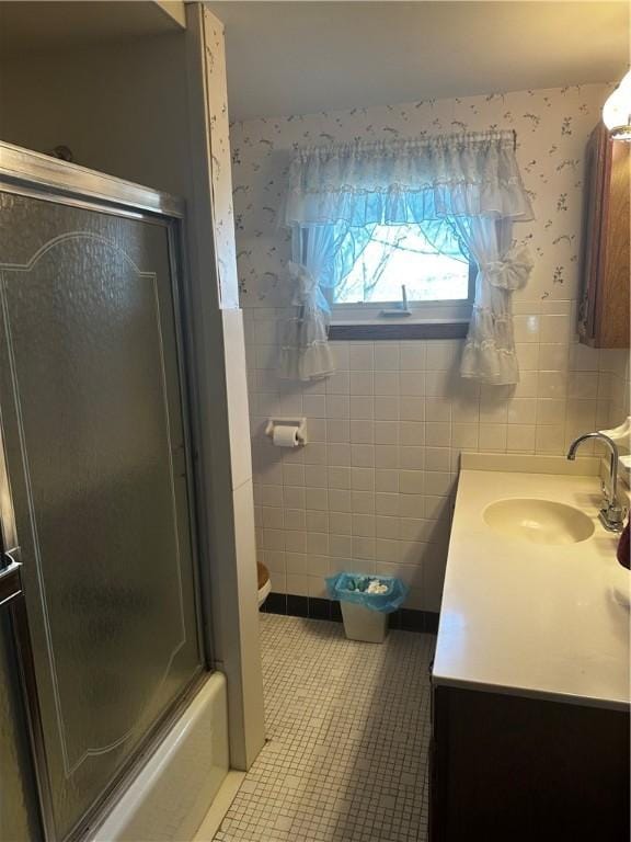 full bathroom featuring vanity, shower / bath combination with glass door, tile patterned flooring, toilet, and tile walls