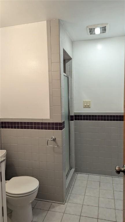 bathroom featuring tile patterned flooring, vanity, toilet, and tile walls