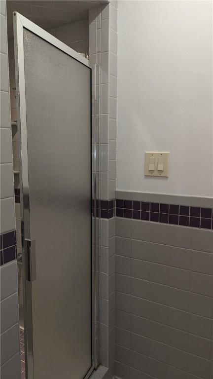 bathroom featuring a shower with shower door and tile walls