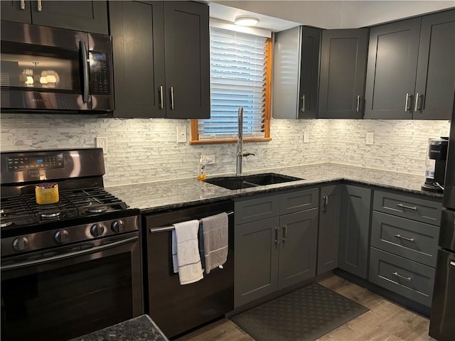 kitchen featuring sink, light hardwood / wood-style flooring, decorative backsplash, stone countertops, and stainless steel appliances