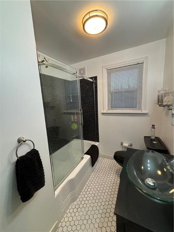 full bathroom featuring vanity, toilet, and shower / bath combination with glass door