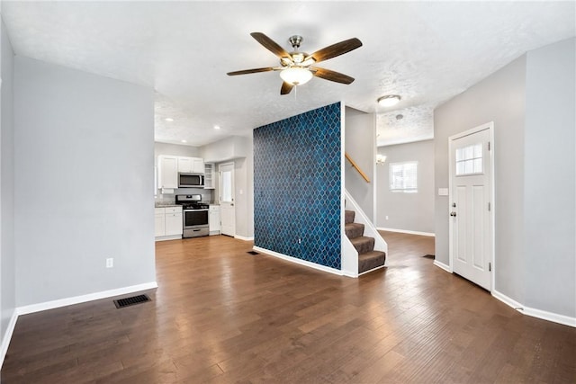 unfurnished living room featuring a textured ceiling, dark wood-type flooring, and ceiling fan with notable chandelier