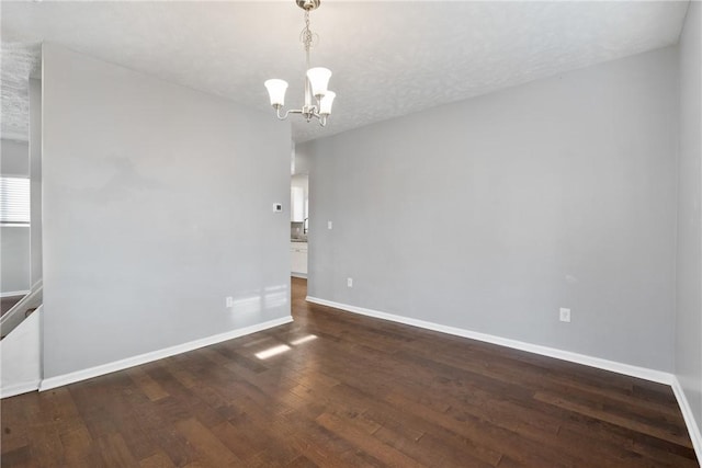 spare room featuring a textured ceiling, a chandelier, and dark hardwood / wood-style floors