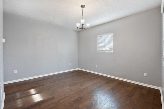 unfurnished room with an inviting chandelier and dark wood-type flooring