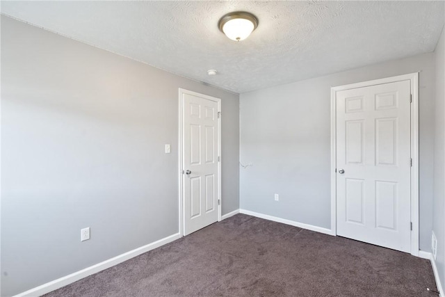 empty room featuring a textured ceiling and dark carpet