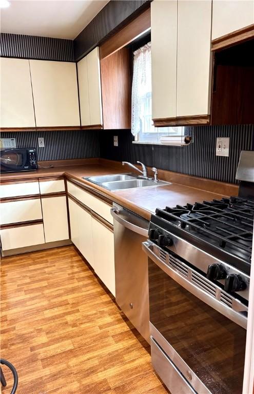 kitchen featuring sink, white cabinetry, stainless steel appliances, and light hardwood / wood-style flooring