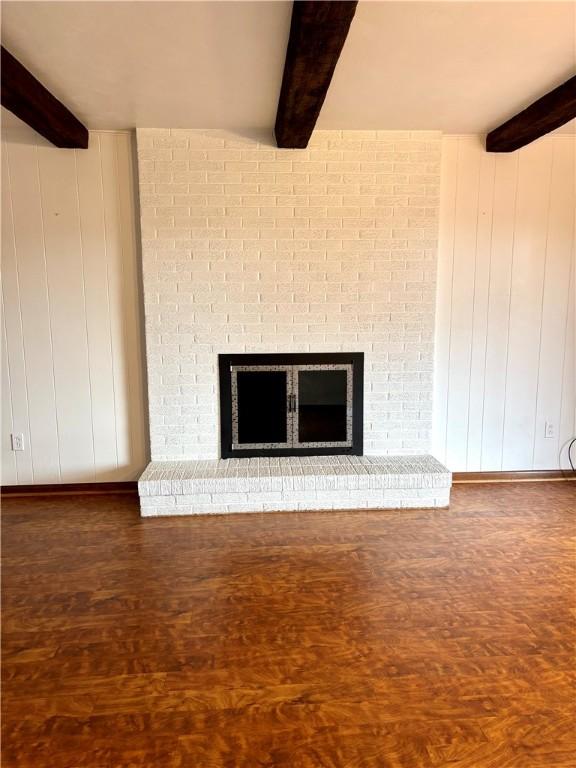 room details with beam ceiling, wood-type flooring, a fireplace, and wooden walls