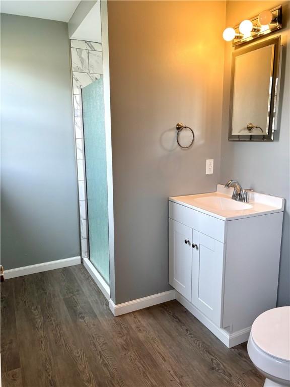 bathroom featuring hardwood / wood-style flooring, vanity, toilet, and a shower with door