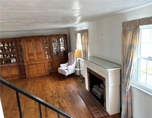 living area with dark wood-type flooring and a brick fireplace