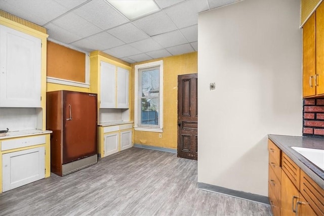 kitchen with white cabinets, a paneled ceiling, light hardwood / wood-style floors, and fridge