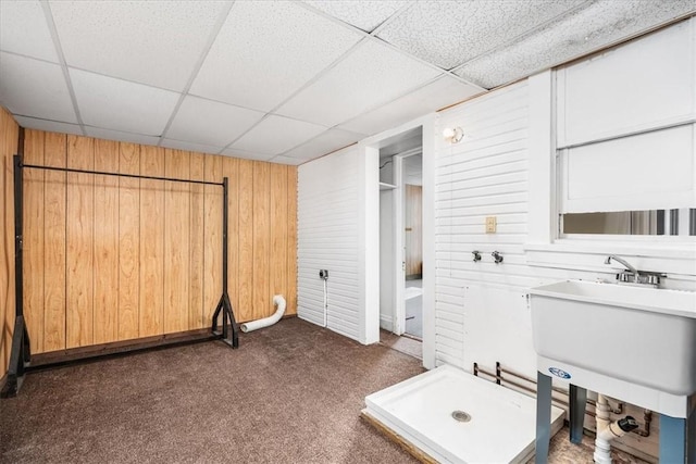 bathroom featuring a paneled ceiling, sink, and wooden walls