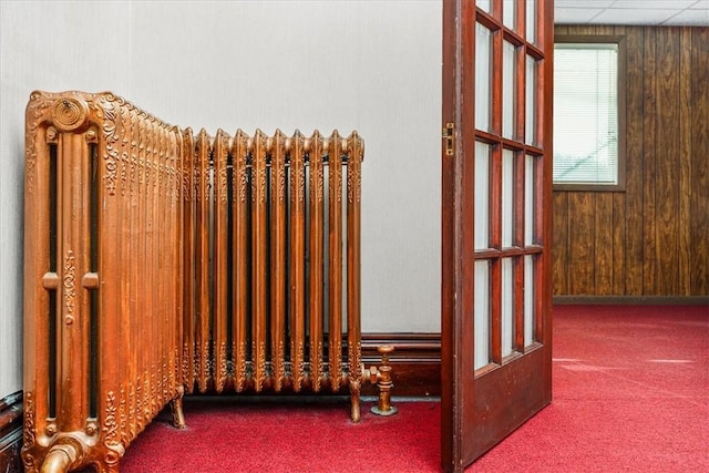 interior space featuring wooden walls, carpet flooring, and radiator