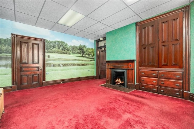 unfurnished living room featuring carpet floors, a water view, and a drop ceiling