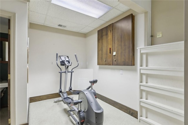 workout room featuring carpet flooring and a paneled ceiling