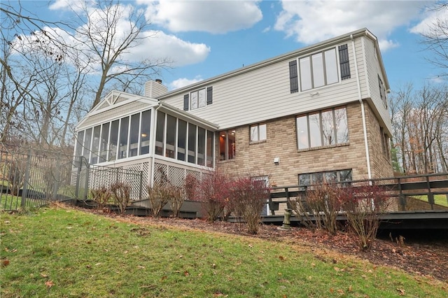 back of property featuring a sunroom, a yard, and a deck