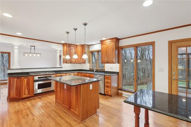 kitchen featuring stainless steel appliances, decorative columns, pendant lighting, a kitchen island, and light wood-type flooring