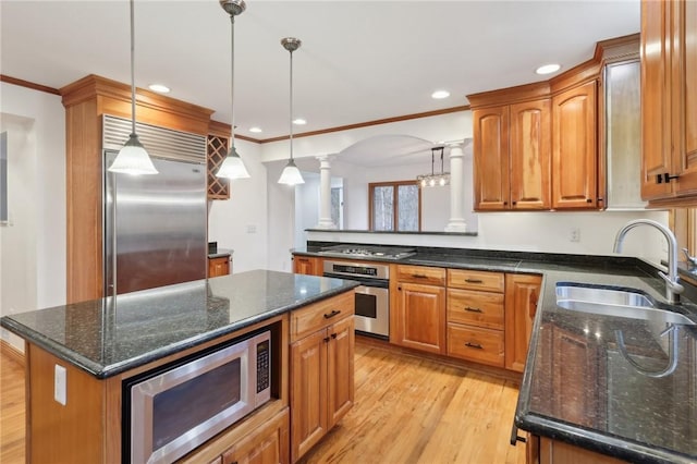 kitchen featuring built in appliances, a center island, pendant lighting, and sink