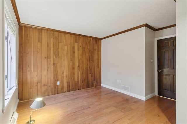 spare room featuring wood-type flooring, wooden walls, and ornamental molding