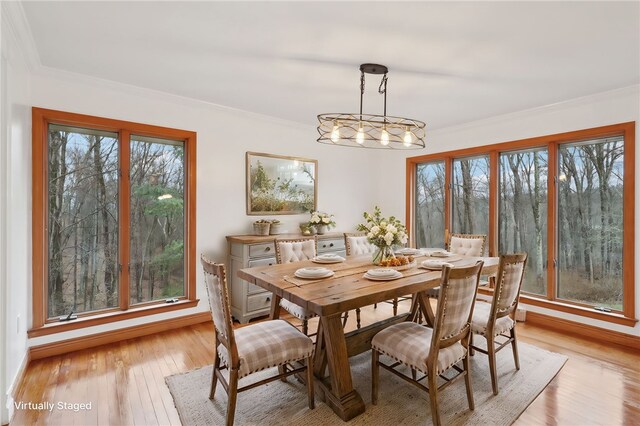 dining area featuring crown molding, light hardwood / wood-style flooring, and an inviting chandelier