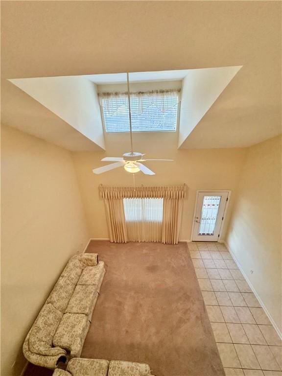 unfurnished living room featuring light tile patterned floors, ceiling fan, and a high ceiling