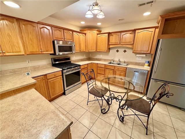 kitchen with backsplash, stainless steel appliances, sink, light tile patterned floors, and a chandelier