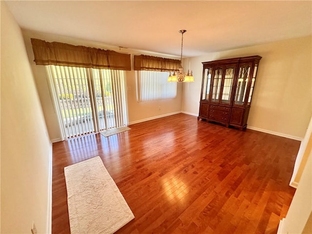 unfurnished dining area featuring a chandelier and dark wood-type flooring