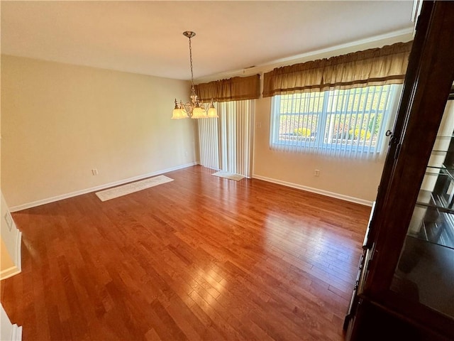 unfurnished dining area with wood-type flooring and a notable chandelier