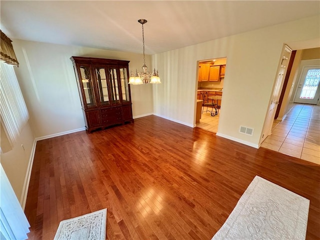 unfurnished dining area featuring hardwood / wood-style floors and a chandelier