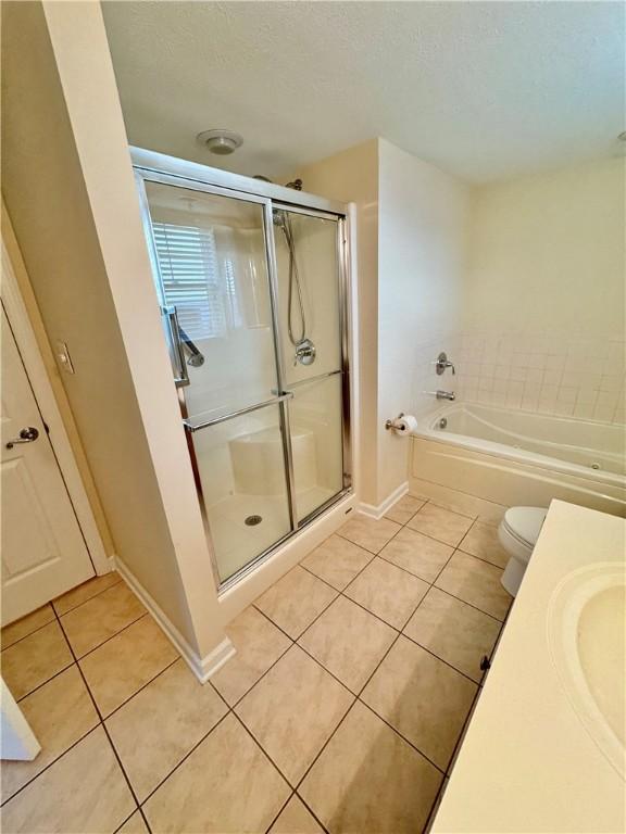 full bathroom featuring tile patterned flooring, a textured ceiling, shower with separate bathtub, toilet, and vanity