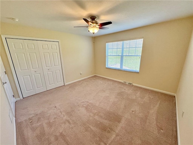 unfurnished bedroom featuring ceiling fan, a closet, and light carpet