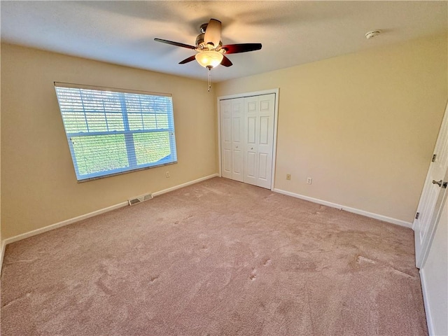 unfurnished bedroom with light carpet, a closet, and ceiling fan