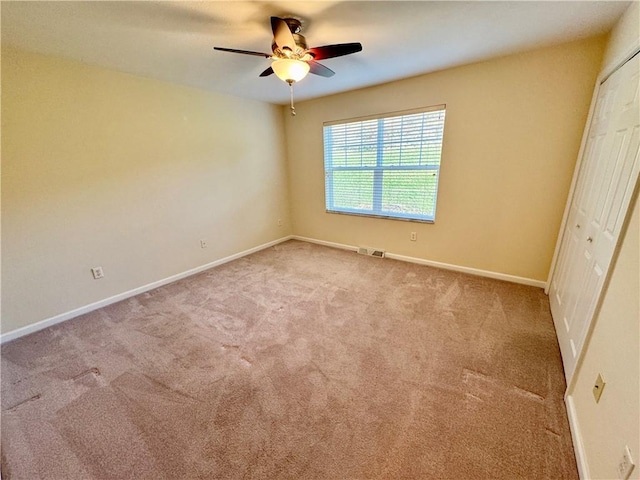 unfurnished bedroom featuring ceiling fan, light carpet, and a closet