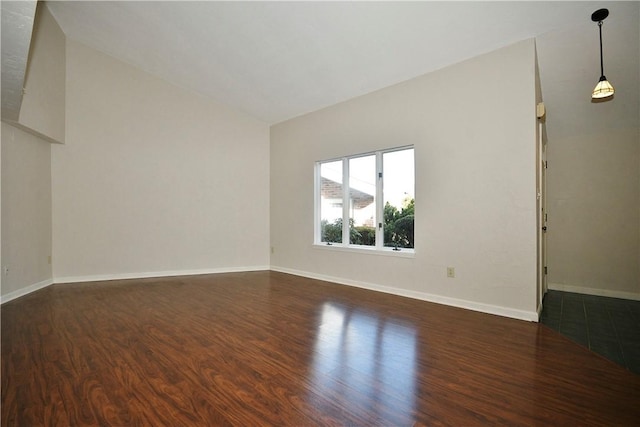 spare room featuring dark wood-type flooring and lofted ceiling