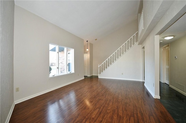 unfurnished living room featuring dark wood-type flooring and lofted ceiling