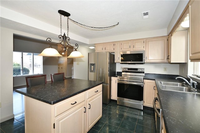 kitchen featuring stainless steel appliances, dark tile patterned floors, sink, decorative light fixtures, and a kitchen island