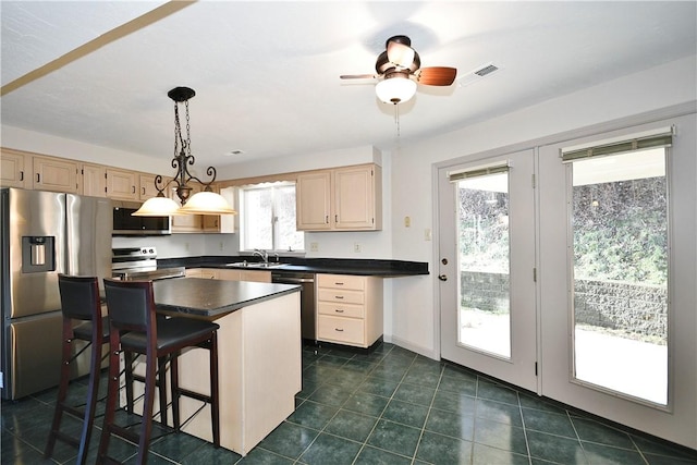 kitchen featuring appliances with stainless steel finishes, a kitchen breakfast bar, ceiling fan, pendant lighting, and a center island