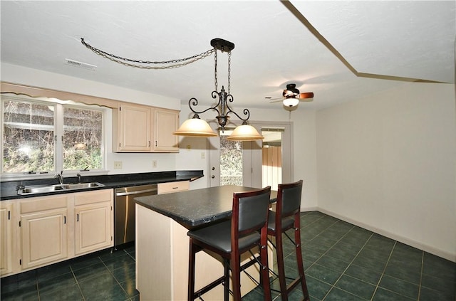 kitchen with a kitchen breakfast bar, ceiling fan with notable chandelier, sink, dishwasher, and a center island