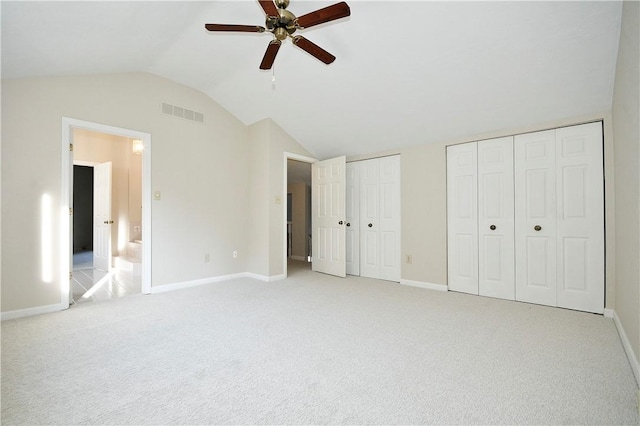 unfurnished bedroom with multiple closets, ceiling fan, light carpet, and lofted ceiling