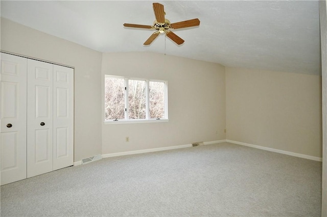 unfurnished bedroom featuring carpet, a closet, vaulted ceiling, and ceiling fan