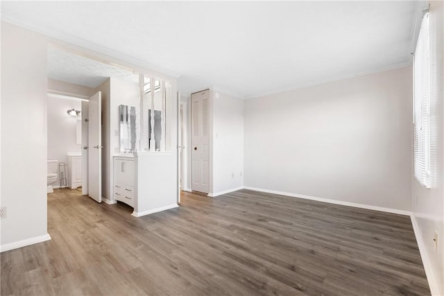 empty room featuring dark wood-type flooring and ornamental molding